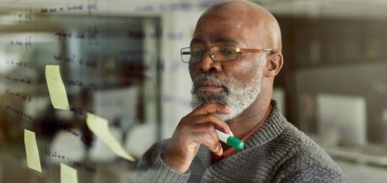 Cropped shot of a mature businessman brainstorming with notes on a glass wall