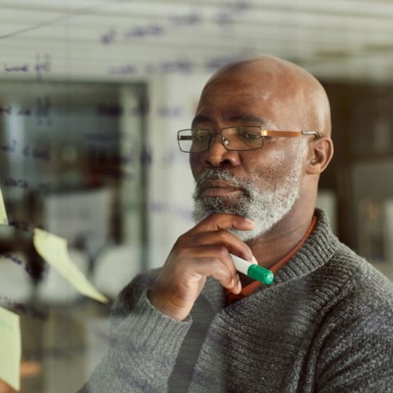 Cropped shot of a mature businessman brainstorming with notes on a glass wall